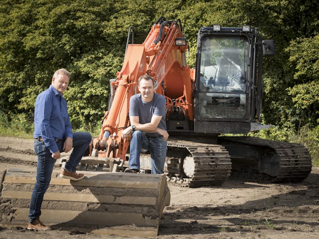 Johan van Apeldoorn (links) en Pim de Jonge bij een Hitachi ZX 135 US-5, die bij de opleiding tot machinist door IPC Werkt wordt ingezet. 'Wij leiden mensen praktisch op. Geen saaie theorielessen, maar zelf op de graafmachine of wiellader.'