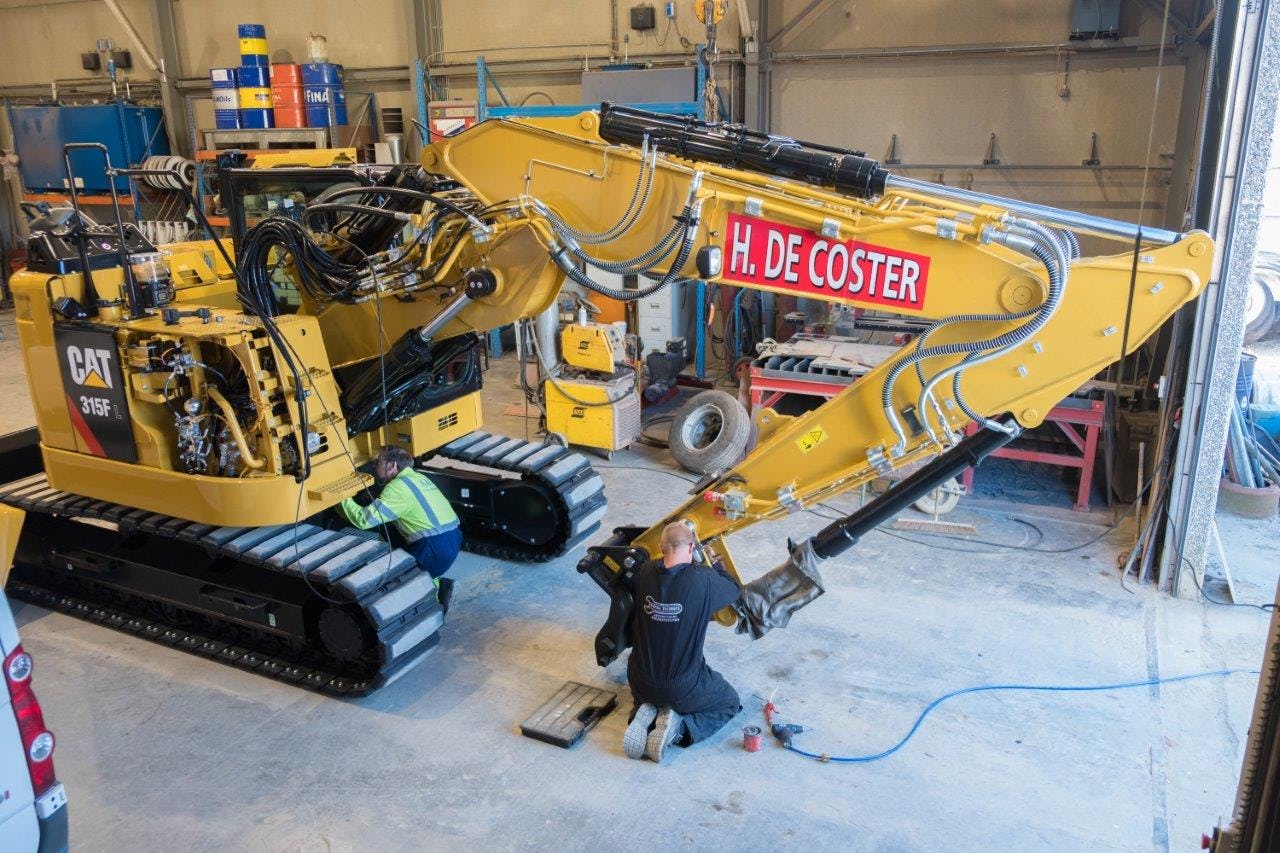 Een Caterpillar 315F wordt in de werkplaats van Henri de Coster in het Belgische Peer door AMC voorzien van een automatisch smeersysteem.