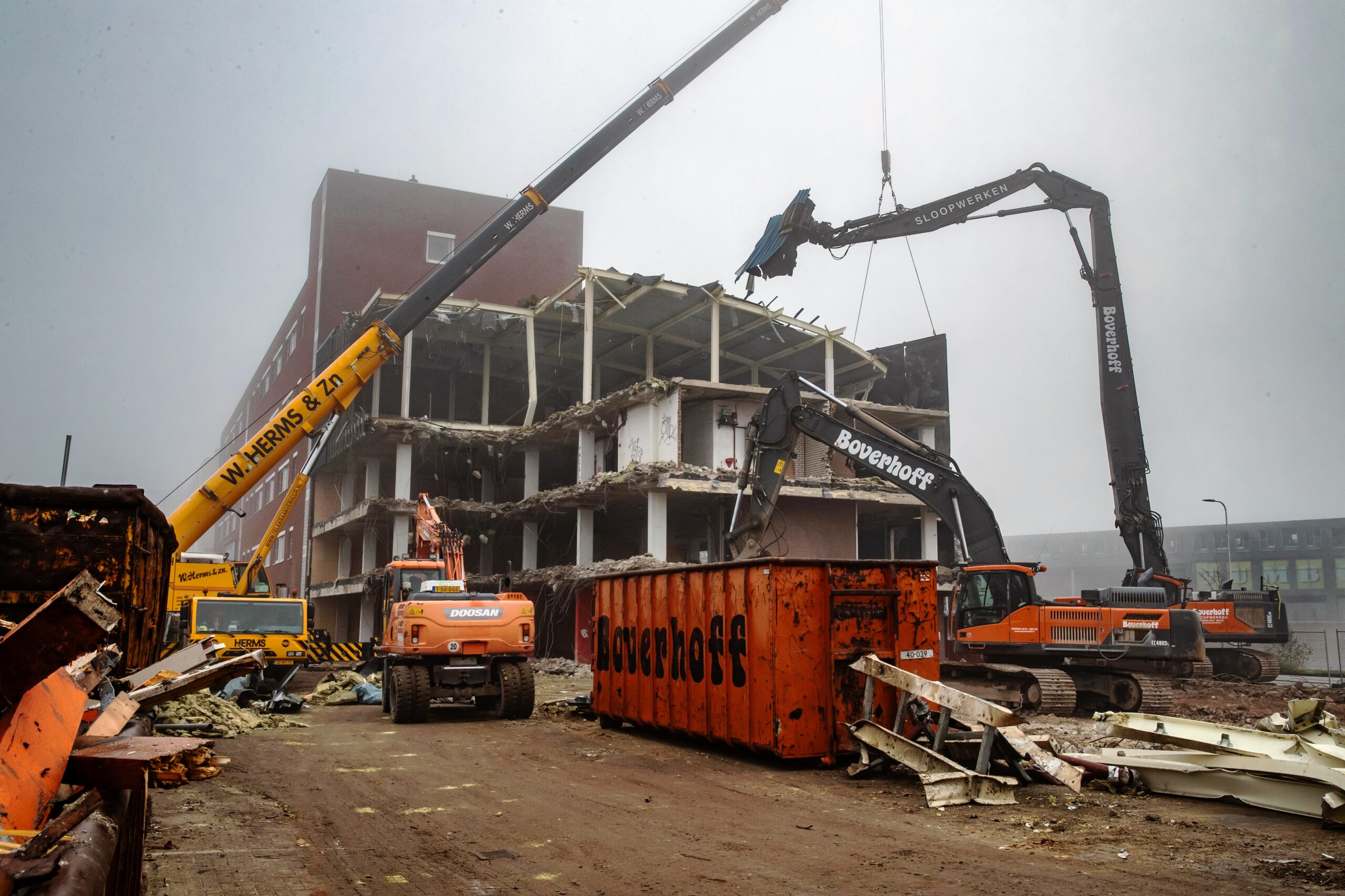 Tijdens de sloop van het laatste deel reikt een telescoopkraan over het gebouw om met een groot scherm het fietspad te vrijwaren van vallend puin. (Foto’s: Ronald Hissink)