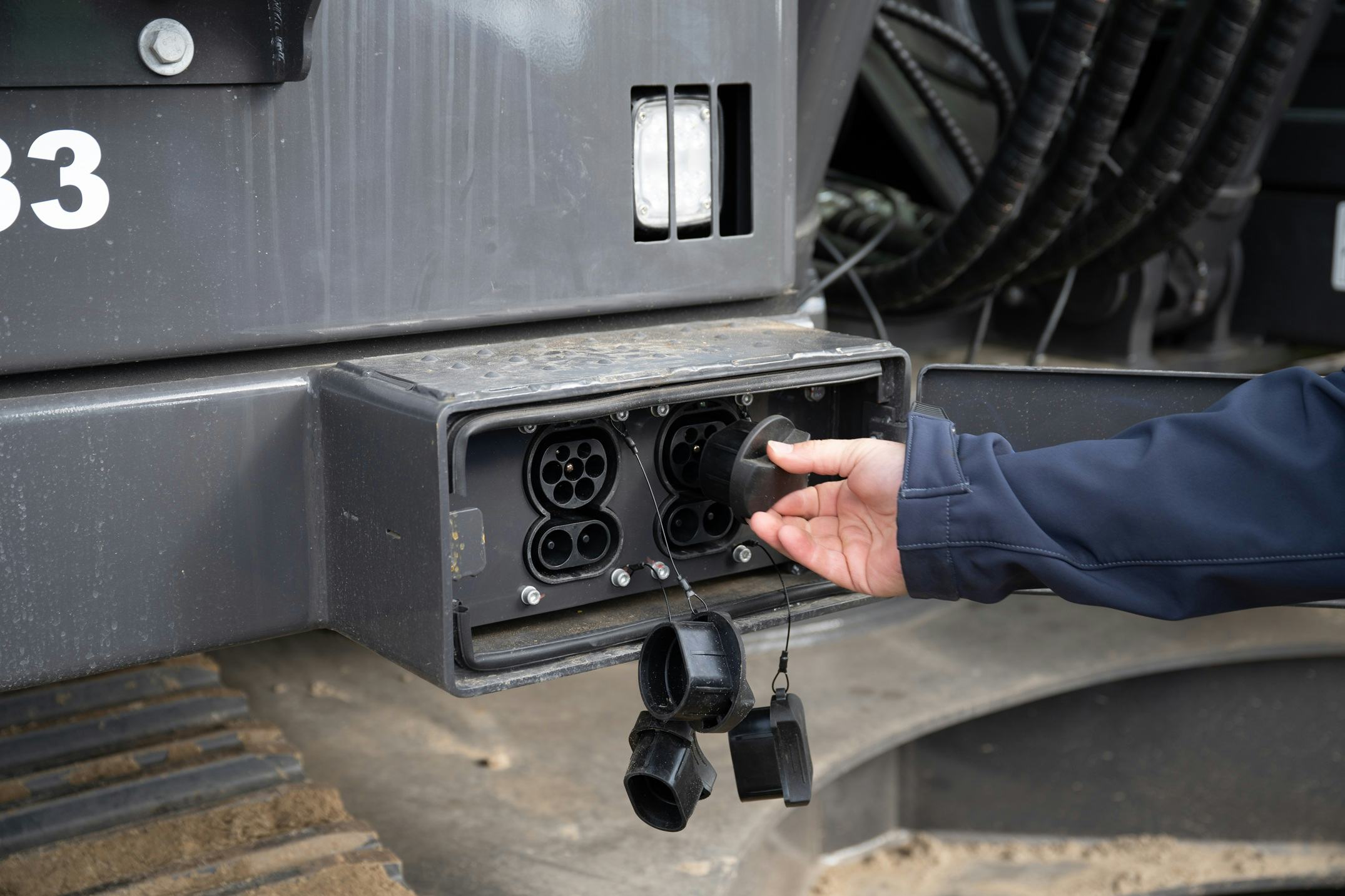 De laadaansluiting bevindt zich achter een klepje aan de voorkant van de machine. Deze zit daarmee ruim binnen het draaibereik van de machine, zodat die niet snel beschadigd wordt.