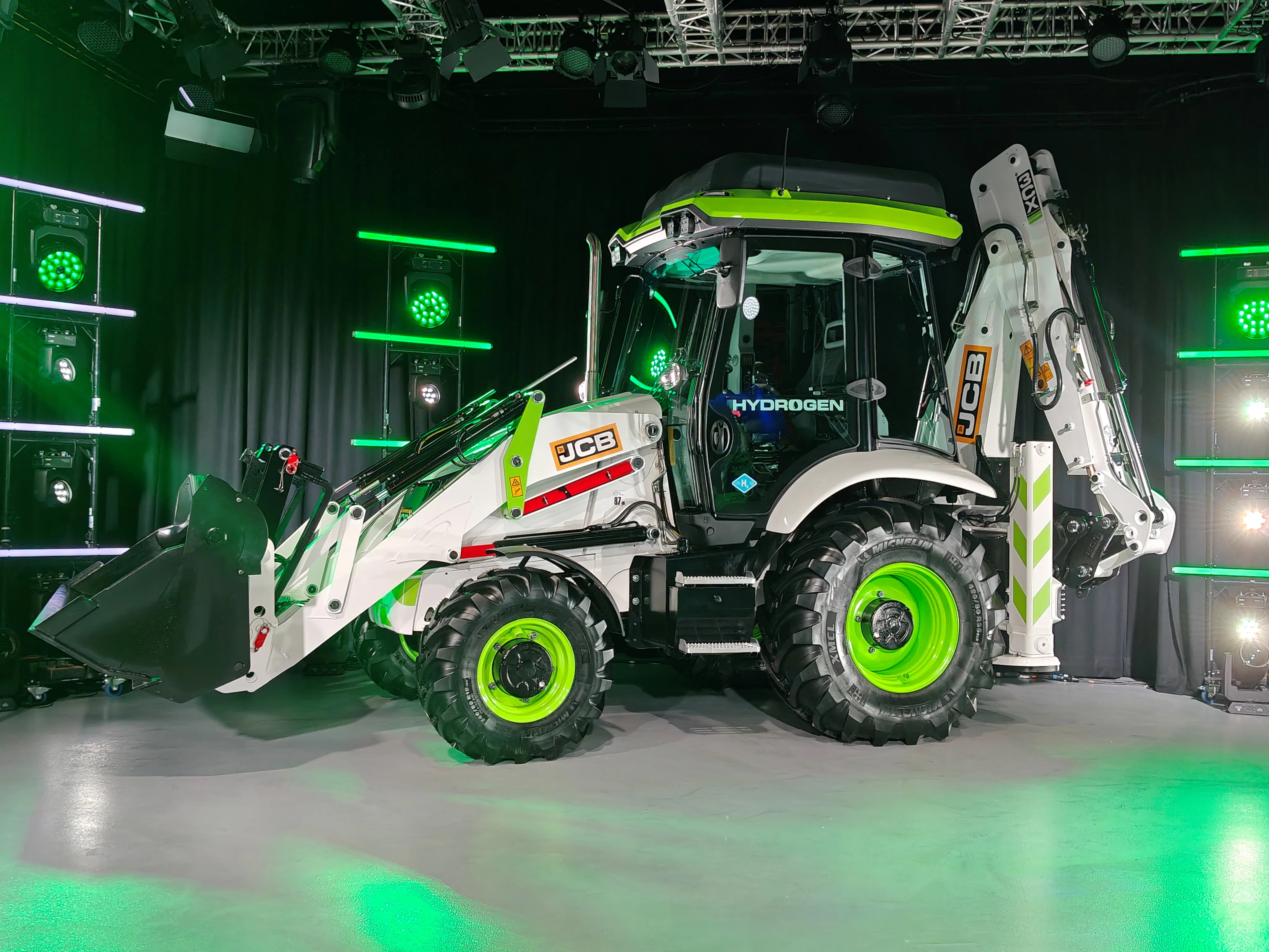 Hier op het podium tijdens de perspresentatie, de volgende ochtend in de regen in de steengroeve van JCB: de 3CX Hydrogen graaflaadcombinatie.